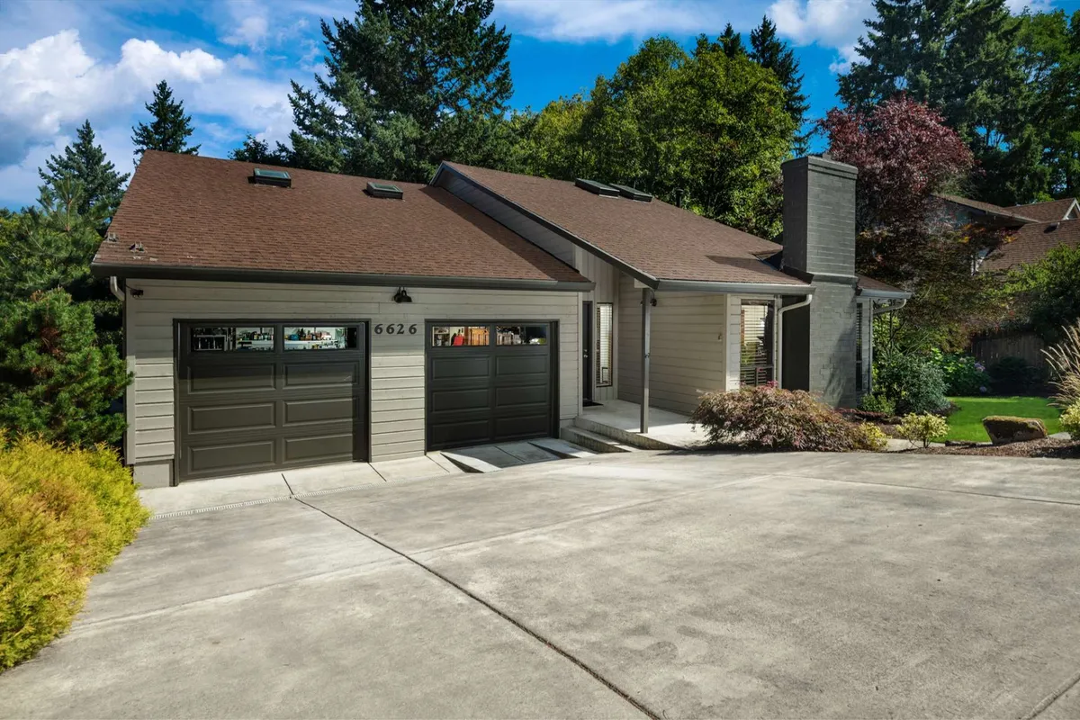 The exterior view of the home's front entrance, including landscaped gardens and garage doors. The setting is warm and approachable, suggesting a welcoming place for gatherings and outdoor activities like barbecues and morning coffee on the porch.