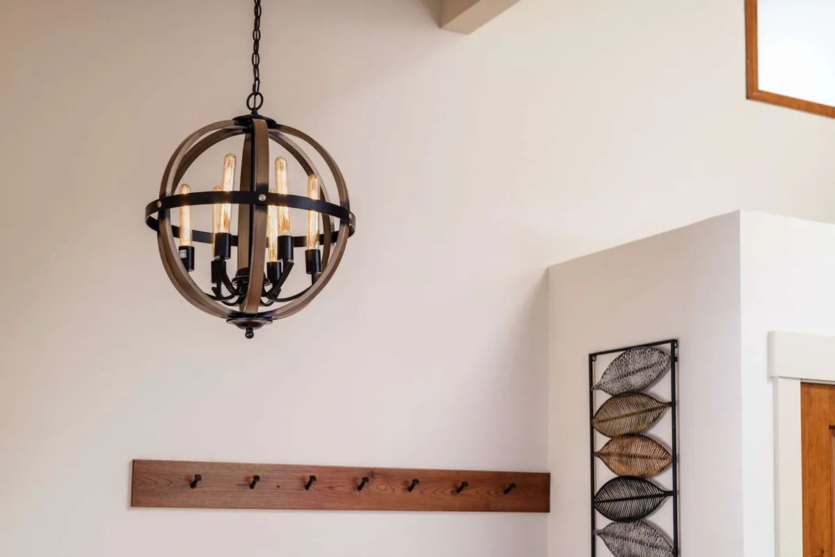 A welcoming entryway accented by a glowing chandelier, tasteful wall art, and a coat rack—suggesting arrivals, greetings, and the start of shared adventures in the home.