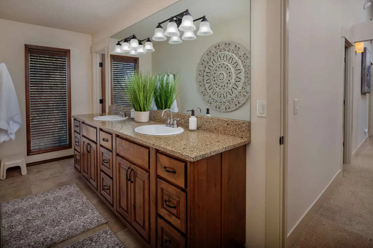 A modern bathroom with a double sink vanity, large decorative wall mirror, and a potted plant. The clean, calming decor sets an inviting tone for morning and evening routines.