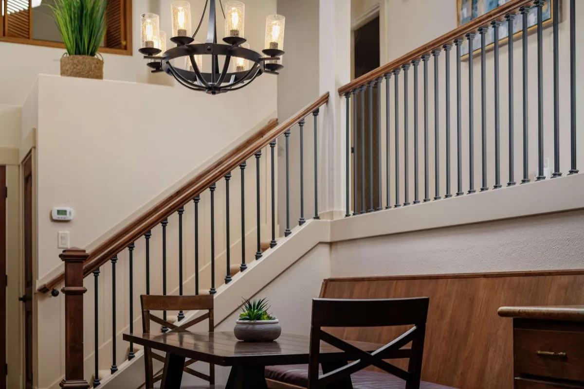 An inviting interior shot of a spacious dining area with a chandelier, a central dining table, and a staircase—perfect for gathering, sharing meals, and socializing as a family after outdoor adventures.